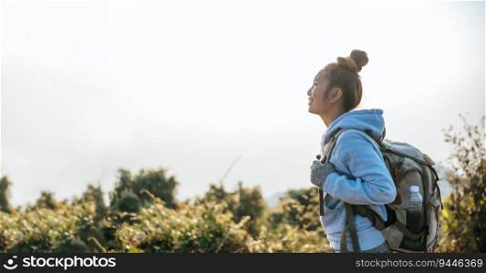 Portrait of Asian young tourist woman is hiking on the top of the mounting and looking at a beautiful landscape with copy space. Travel Lifestyle wanderlust adventure concept vacations outdoor.