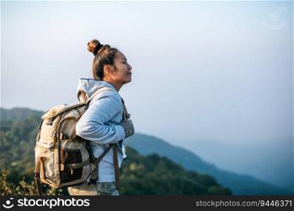 Portrait of Asian young tourist woman is hiking on the top of the mounting and looking at a beautiful landscape with copy space. Travel Lifestyle wanderlust adventure concept vacations outdoor.