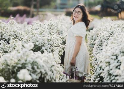 Portrait of asian Young woman happy traveler with white dress enjoying in white blooming or White margarita flowe field in the garden of in Chiang Mai,Thailand,travel relax vacation