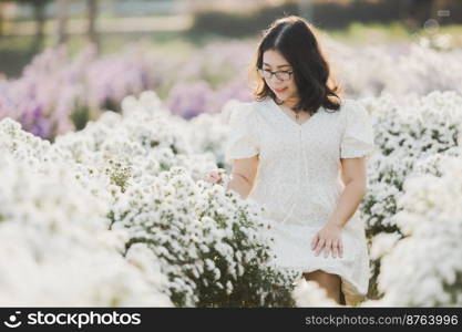 Portrait of asian Young woman happy traveler with white dress enjoying in white blooming or White margarita flower field in the garden of in Chiang Mai,Thailand,travel relax vacation