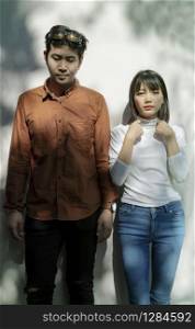 portrait of asian younger man and woman like fashion model standing against beautiful light wall