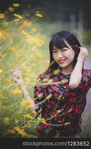 portrait of asian younger standing beside yellow cosmos flower blooming field