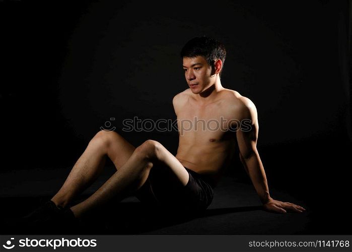 portrait of athletic muscular bodybuilder man with naked torso doing sit up exercise. fitness workout concept