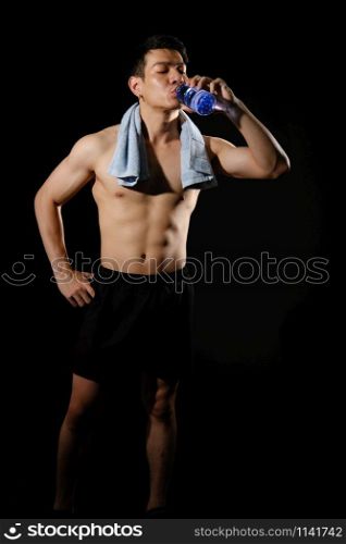 portrait of athletic muscular bodybuilder man with naked torso six pack abs drinking water. fitness workout concept