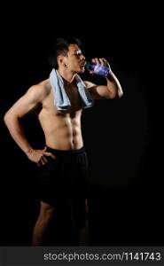 portrait of athletic muscular bodybuilder man with naked torso six pack abs drinking water. fitness workout concept
