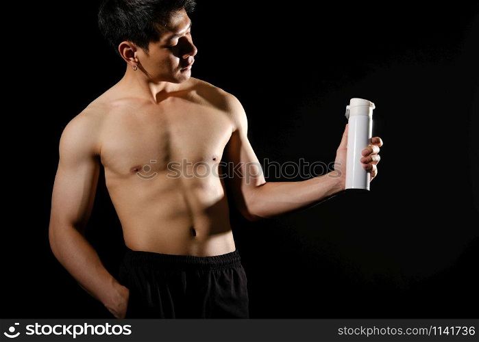 portrait of athletic muscular bodybuilder man with naked torso six pack abs holding protein drink. fitness workout concept