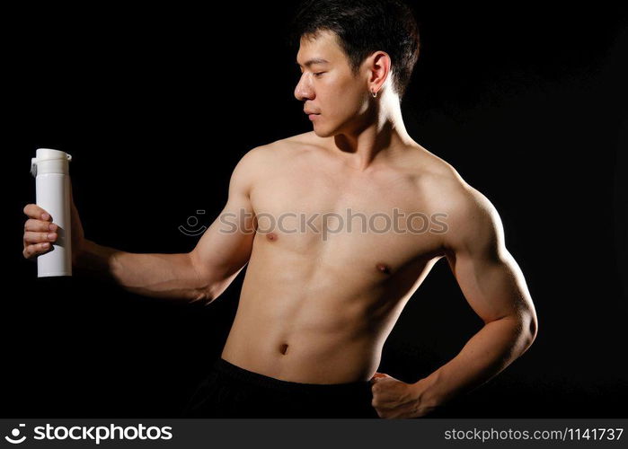 portrait of athletic muscular bodybuilder man with naked torso six pack abs holding protein drink. fitness workout concept