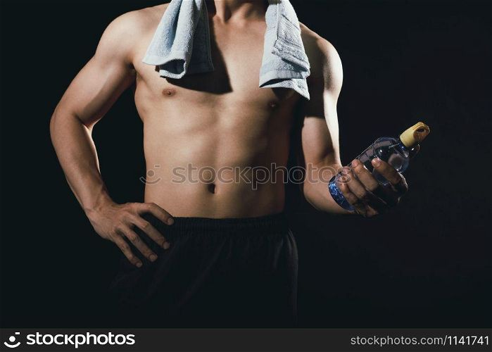 portrait of athletic muscular bodybuilder man with naked torso six pack abs holding water bottle. fitness workout concept