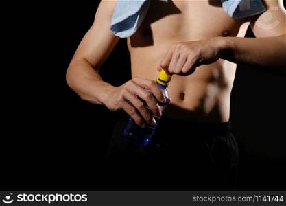 portrait of athletic muscular bodybuilder man with naked torso six pack abs holding water bottle. fitness workout concept