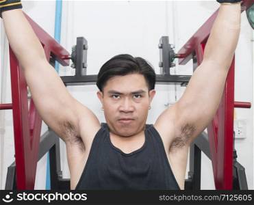portrait of athletic young man flexing chest muscles on gym machine