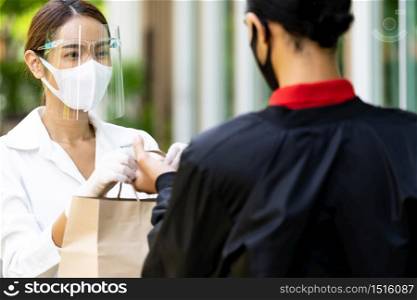 Portrait of atrractive asian woman give bakery grocery bag to delivery man to deliver it to customer make online order. Food delivery service concept in new normal after coronavirus pandemic.