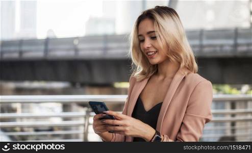 Portrait of attractive beautiful American business woman in formal uniform chat, shop online, check email, using corporate applicaiton on smart phone in city. Smile happy woman with delight face.