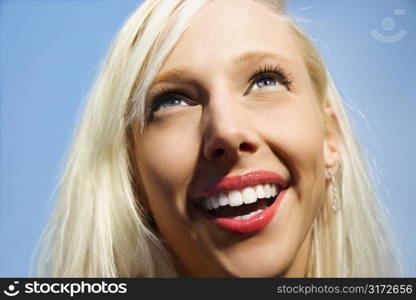 Portrait of attractive blonde Caucasian young adult woman smiling and looking up.