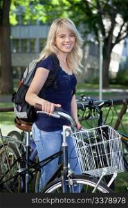 Portrait of attractive blonde female student standing with her bike