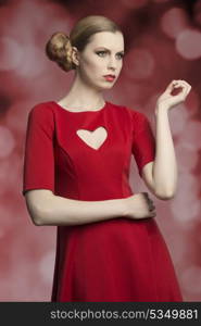 portrait of attractive blonde girl with cute hair-style and make-up posing with romantic style wearing red dress with sexy heart shaped neckline