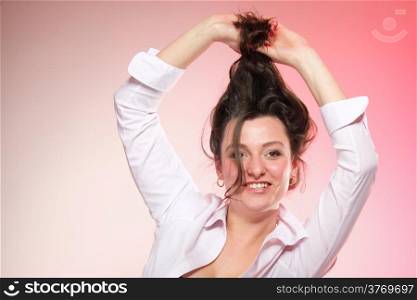 portrait of attractive caucasian smiling woman brunette holding her long healthy hair pink background studio shot