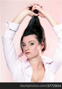 portrait of attractive caucasian woman brunette holding her long healthy hair pink background studio shot
