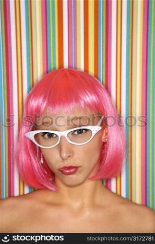 Portrait of attractive Caucasian young adult woman wearing pink wig against striped background looking at viewer.
