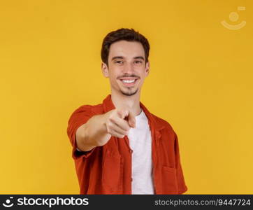 Portrait of attractive cheerful young man pointing finger at camera and standing isolated over background. People and lifestyle concept.