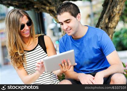Portrait of attractive couple with tablet computer in urban background