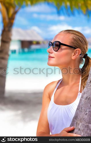 Portrait of attractive female wearing stylish sunglasses and taking sun on the beach, luxury summer vacation, travel and tourism concept