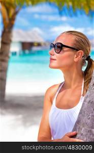 Portrait of attractive female wearing stylish sunglasses and taking sun on the beach, luxury summer vacation, travel and tourism concept