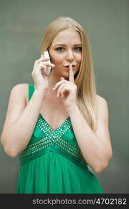 Portrait of attractive girl with finger on lips, concept of student show quiet, silence, secret gesture, young pretty blonde woman in green dress