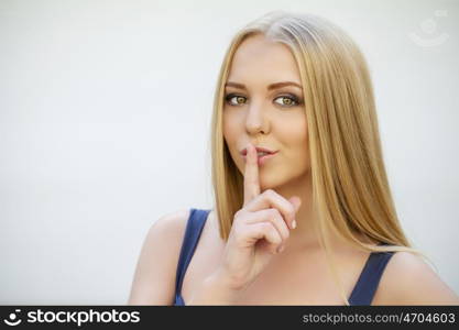 Portrait of attractive girl with finger on lips, concept of student show quiet, silence, secret gesture, young pretty blonde woman in green dress