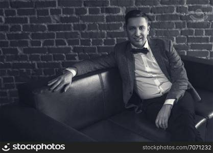 portrait of attractive man in suit on brick wall background