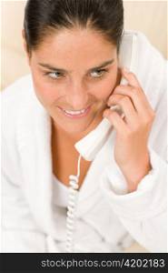 Portrait of attractive mid-aged woman speaking on phone wearing bathrobe
