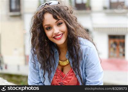 Portrait of attractive mixed woman in urban background wearing casual clothes
