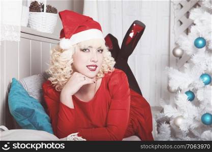 Portrait of attractive santa girl blonde on the background of the Christmas tree.