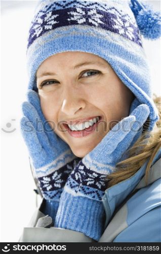Portrait of attractive smiling mid adult Caucasian woman wearing blue ski cap and gloves looking at viewer.