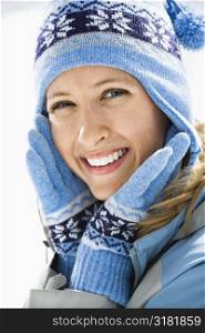 Portrait of attractive smiling mid adult Caucasian woman wearing blue ski cap and gloves looking at viewer.