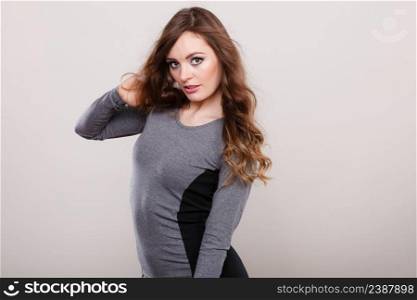 Portrait of attractive woman having long brown curly hair wearing grey dress. Portrait of attractive woman wearing grey dress