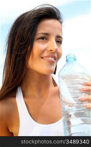Portrait of attractive woman holding bottle of water outside