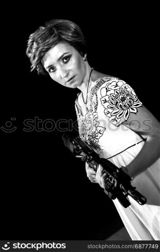 Portrait of attractive woman in military style holding gun in hands