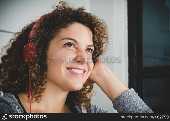 Portrait of attractive woman listening to music while lying on sofa in living room