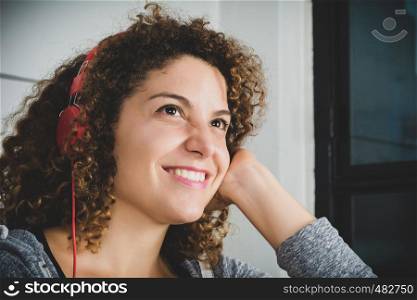 Portrait of attractive woman listening to music while lying on sofa in living room