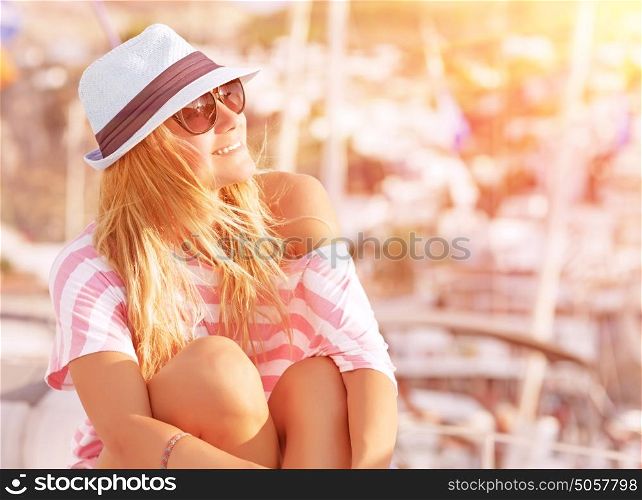 Portrait of attractive woman relaxing on luxury sailboat, enjoying mild sunset light, summer fashion and style concept