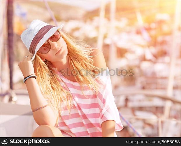 Portrait of attractive woman relaxing on luxury sailboat, enjoying mild sunset light, summer fashion and style concept