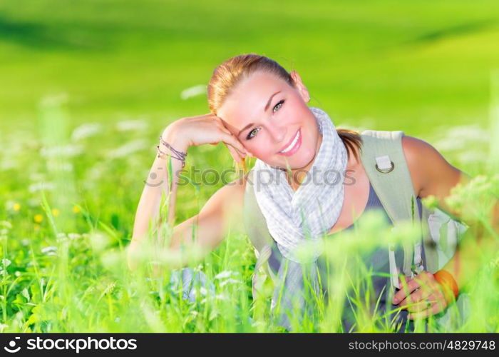 Portrait of attractive woman sitting on floral meadow, trekking along countryside, summertime travel and tourism concept