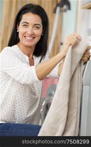 portrait of attractive woman taking clothes out washing machine