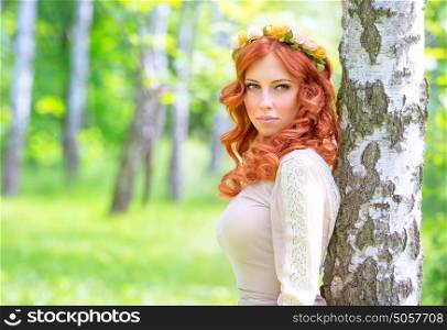 Portrait of attractive woman with red hair in the park, wearing gentle flowers wreath and stylish dress, fashion and vogue concept