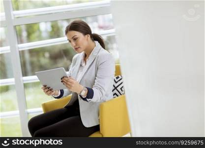 Portrait of attractive young business woman working online with a digital tablet while sittingin the modern office
