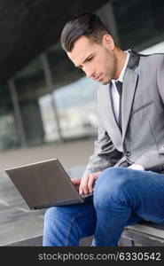 Portrait of attractive young businessman typing in a laptop computer in office building