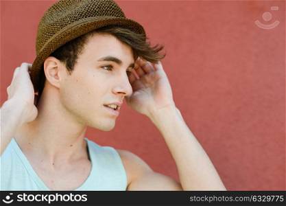 Portrait of attractive young man in urban background wearing a sun hat