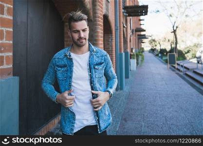 Portrait of attractive young man walking on the street with backpack on his shoulders. Urban concept.