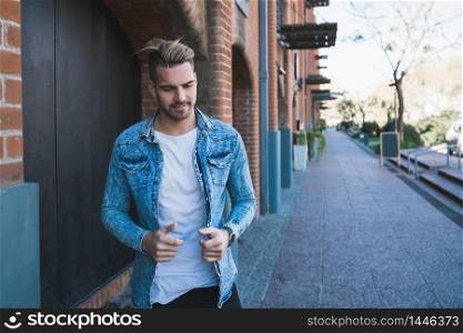 Portrait of attractive young man walking on the street with backpack on his shoulders. Urban concept.
