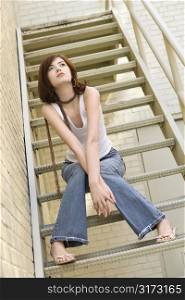 Portrait of attractive young redhead Caucasian woman sitting on fire escape.